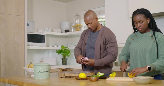 African American couple prepping dinner peeling onion slicing pepper tossing scraps into compost