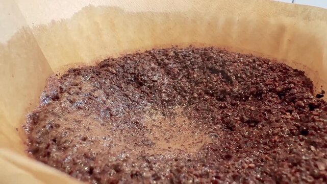 Wet Coffee Grounds Settling in a Paper Filter Close Up