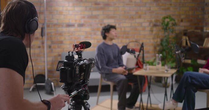 Crew filming talk cueing cam operator adjusting camera and monitoring mic for studio interview