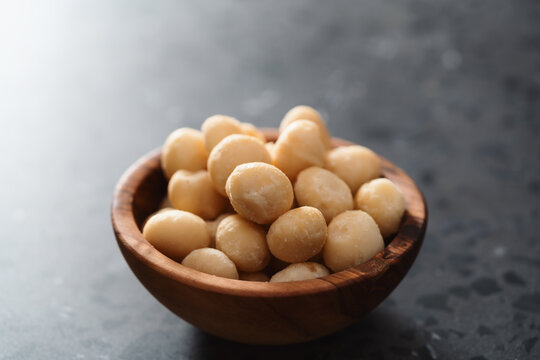 Macadamia nuts in olive wood bowl on terrazzo surface