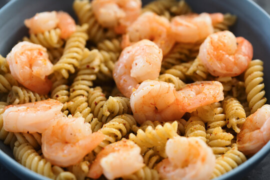 Fusilli with shrimps and pesto in a blue bowl