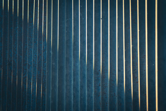 Corrugated metal sheet texture background with vertical lines and dramatic natural sunlight. This high-quality stock photograph showcases a dark blue metallic surface featuring subtle rust details,