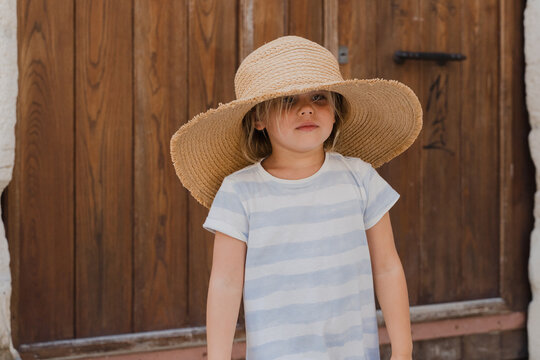 Cute young girl wearing a large straw hat outside