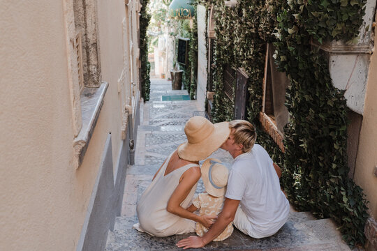 Family with toddler kissing on steps in a picturesque alley