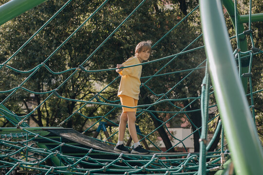 Young boy playing on a rope climbing structure in a park