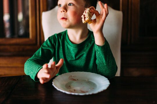 Young boy in a green shirt eating a sandwich