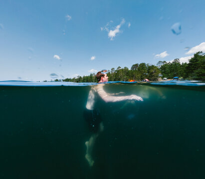 Split level view of a man swimming in a dark lake