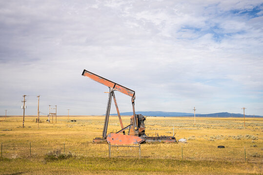 An old rusty oil pump sits in a vast prairie