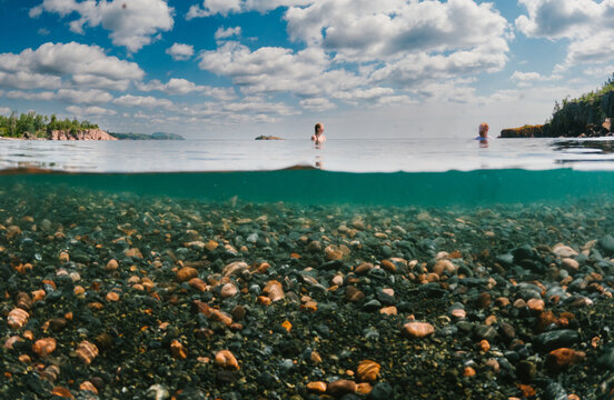 Over under split shot of people swimming in a lake