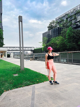 Full length shot of an Asian woman in activewear checking her smartwatch during an outdoor workout in a modern urban park