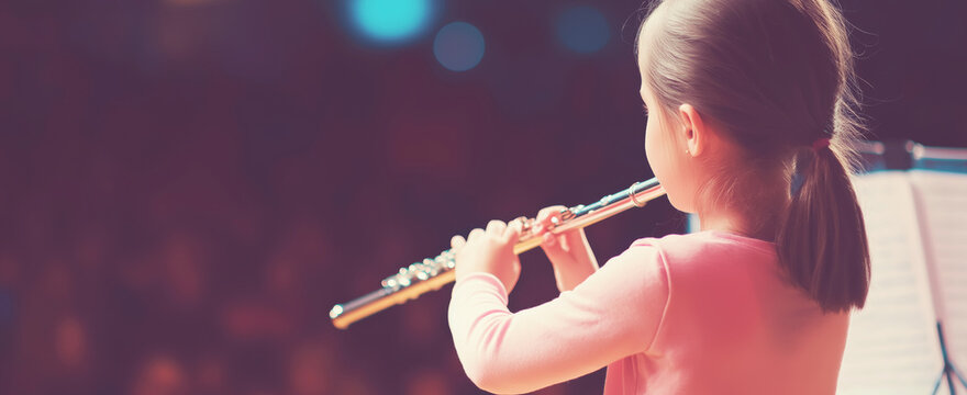 Little girl performing flute on stage, learning classical music, developing talent and skill