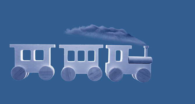 Wooden toy train generating smoke cloud on blue background