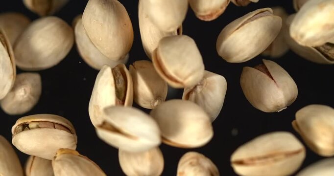 Pistachios falling in slow motion on black background top view