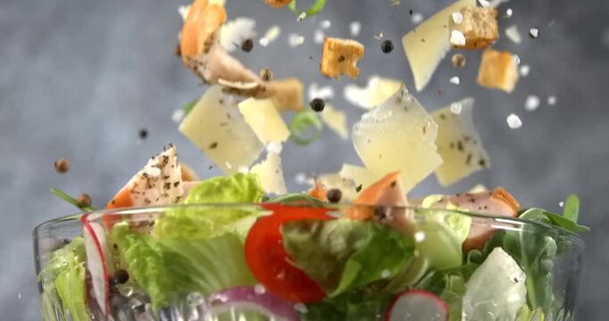 Caesar salad ingredients falling into a bowl in slow motion