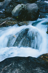 Waterfall cascading over rocks in lush green forest at a hill station in India. Scenic Himalayan nature landscape, ideal for travel, tourism and outdoor themes. © Sanket Mishra