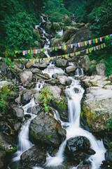 Waterfall cascading over rocks in lush green forest at a hill station in India. Scenic Himalayan nature landscape, ideal for travel, tourism and outdoor themes. © Sanket Mishra