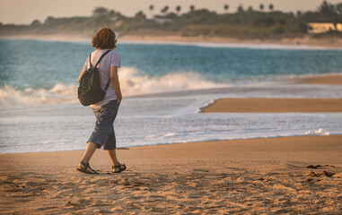 Senior female traveler walking along sunny Cadiz beach in Spain © Paolo Corazza