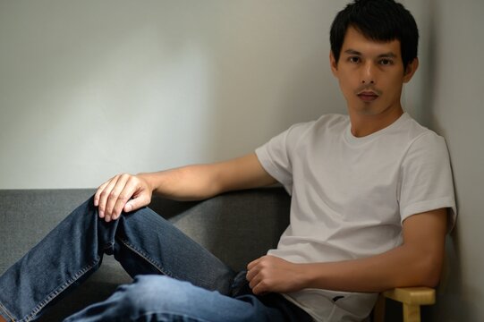 Young Man Relaxing in Casual White Shirt on Comfortable Sofa