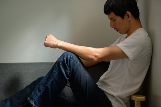 Thoughtful Young Man Sitting on Couch in Casual Interior Setting