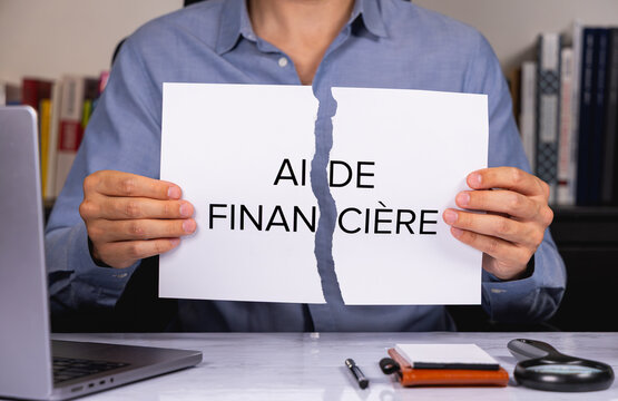 Une personne en chemise tenant une feuille de papier d&eacute;chir&eacute;e sur laquelle est &eacute;crit en gros les mots aide financi&egrave;re.
