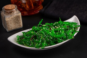 Chuka salad with green seaweed topped with white sesame seeds in white ceramic bowl, Japanese appetizer side dish © Andrei Starostin