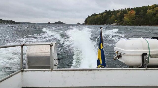 Close up view of water taxi leaving foamy wake on Baltic Sea against background of forested islands. Sweden.