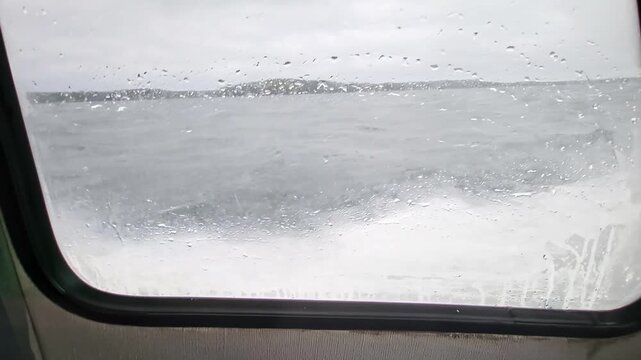 Close-up view of sea spray splashing against water taxi window while crossing rough Baltic Sea. Sweden.
