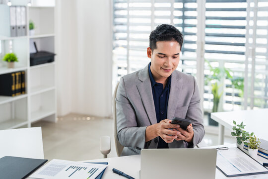 Business man manager trader using cell phone mobile app holding smartphone in office for trading, reading, working online sitting at desk.