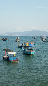 Scenic panoramic view of traditional wooden fishing boats anchored in the sea bay against modern city skyline of Nha Trang, Vietnam. Travel, coastal cityscape and tourism concept.