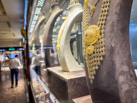 Row of display busts carrying gold necklaces along a jeweller counter in the gold souk of Deira, Dubai, United Arab Emirates