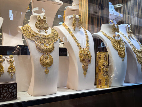 Heavy gold jewellery sets displayed on busts in a jeweller window in the gold souk of Deira, Dubai, United Arab Emirates