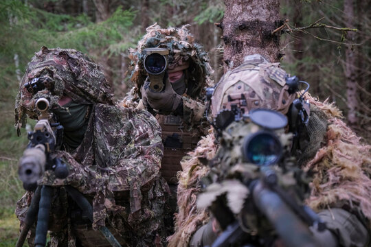 French sniper and spotter lying side by side during multinational forest training in Tapa, Estonia