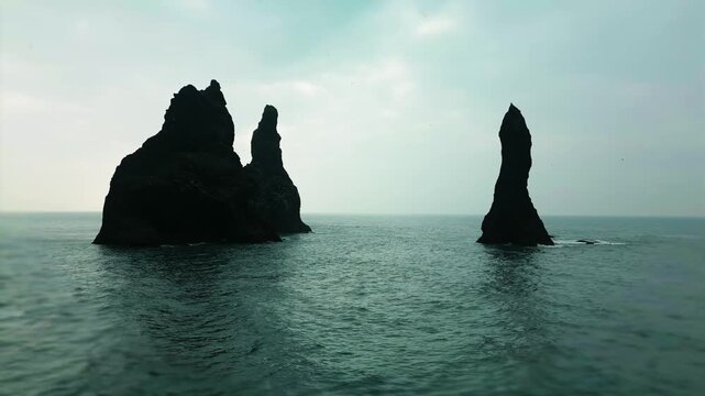 Aerial drone view of Reynisdrangar basalt sea stacks and Atlantic waves, V&iacute;k, Iceland