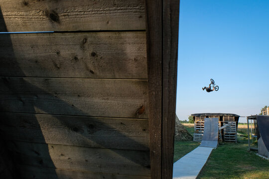 BMX dirt jump framed by the timber of a wooden ramp on a private trail park in Haute-Garonne, France