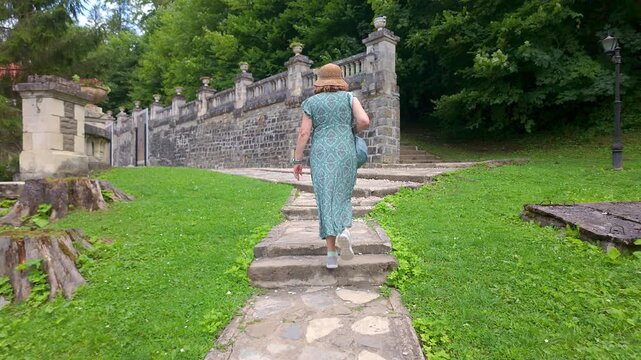 Female tourist walking up stone steps beside a historic balustrade at Cantacuzino Castle in Busteni Romania