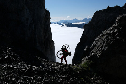 Mountain biker fills the gap between two rock towers on a ridge of the Pyrenees, Aragnouet, France