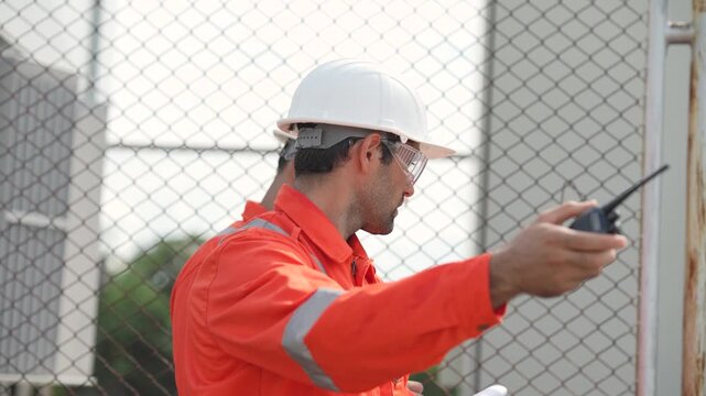 Engineer stands beside industrial tranformer, machinery, observing equipment condition, discussing site inspection findings. Infrastructure maintenance and safety monitoring.