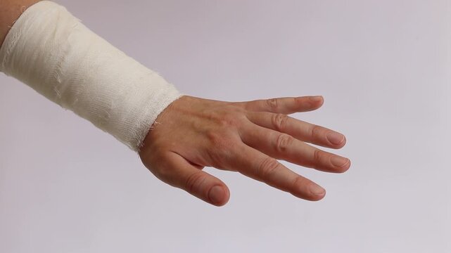 Wrist bandaged with a medical bandage on a light neutral background. A person with a hand injury and a gauze bandage, isolated on a white background. First aid, applying a bandage