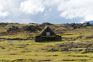 Obraz premium Turf roofed hut on a moss covered heath under dramatic sky