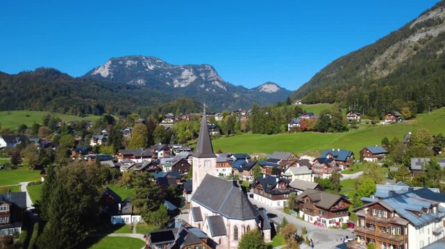 Aerial Drone Forward Flight over Historic Altaussee Church and Traditional Alpine Village with Scenic Mountain Panorama in Austria