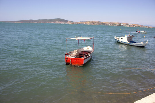 Small traditional fishing boats moored in the calm turquoise sea waters of Ayvalik, Turkey