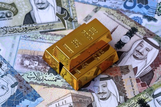 Saudi riyal money bills and gold bullion bars. Saudi Arabia cash bills of SAR currency close up