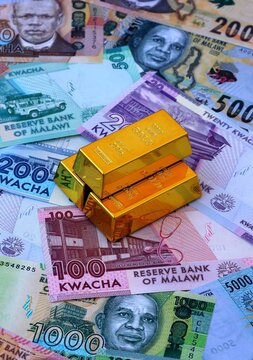 Malawian kwacha money bills and gold bullion bars. Malawi cash bills of MWK currency close up