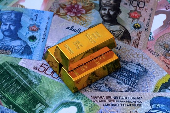 Brunei dollar money bills and gold bullion bars. Brunei cash bills of BND currency close up