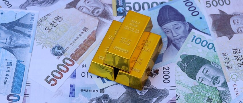 South Korean won money bills and gold bullion bars. South Korea cash bills of KRW currency close up