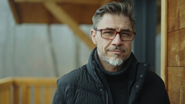 Portrait of middle aged man in eyeglasses and casual cloth outdoor on home balcony. Gray hair, trust and skill, smart older male. Confident smiling. Autumn or winter .