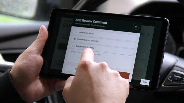 Executive reviews a software license budget request on a tablet, requesting changes and adding feedback as part of a digital corporate spending approval workflow.