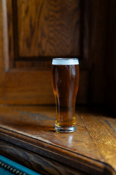 Glass of non alcoholic light beer on dark wood window sill