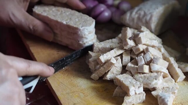 Close-up shot of a person slicing traditional fermented soybean cake