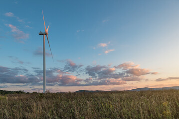 Single wind turbine in field at beautiful sunset sky with pink clouds. © Volodymyr Shevchuk